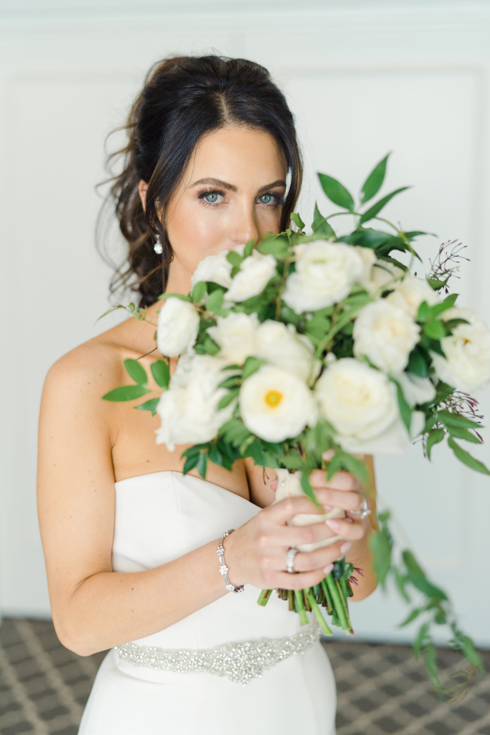 gorgeous blue eyed bride holds a bouquet of white florals while getting ready at bel-aire bay club